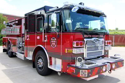 A red pumper fire truck with a red and black cab is parked with the cab in the foreground showcasing the chassis. 