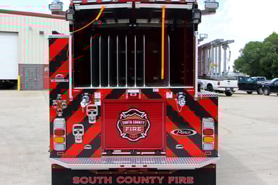 An image of the back of a pumper fire truck features red and black chevon stripes and lots of compartment space for hose storage. 
