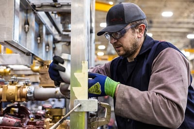 A fire truck manufacturing team members assembling a pump for a fire truck in a modern manufacturing facility.