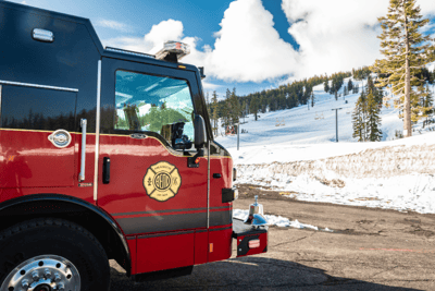 A red and black fire truck with gold emblem sitting on the side of a mountainside.