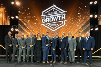 A team of sales professionals in front of a screen from a sales meeting.
