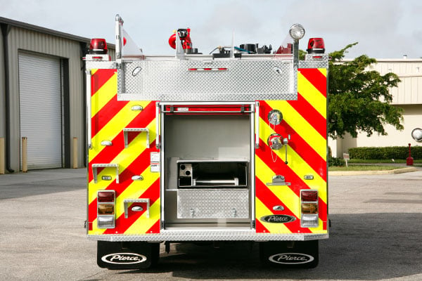 Rear compartment of a Pierce Pumper Responder Fire Truck parked outside near a building. 