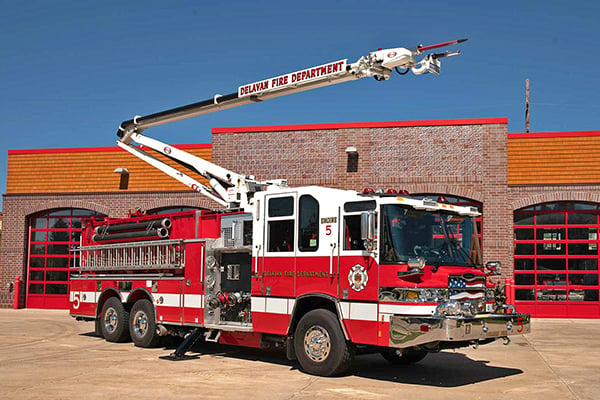 Pierce Fire Truck parked outside on a sunny day in front of a Fire Station with the High-Reach Snozzle extended out in front of the apparatus. 