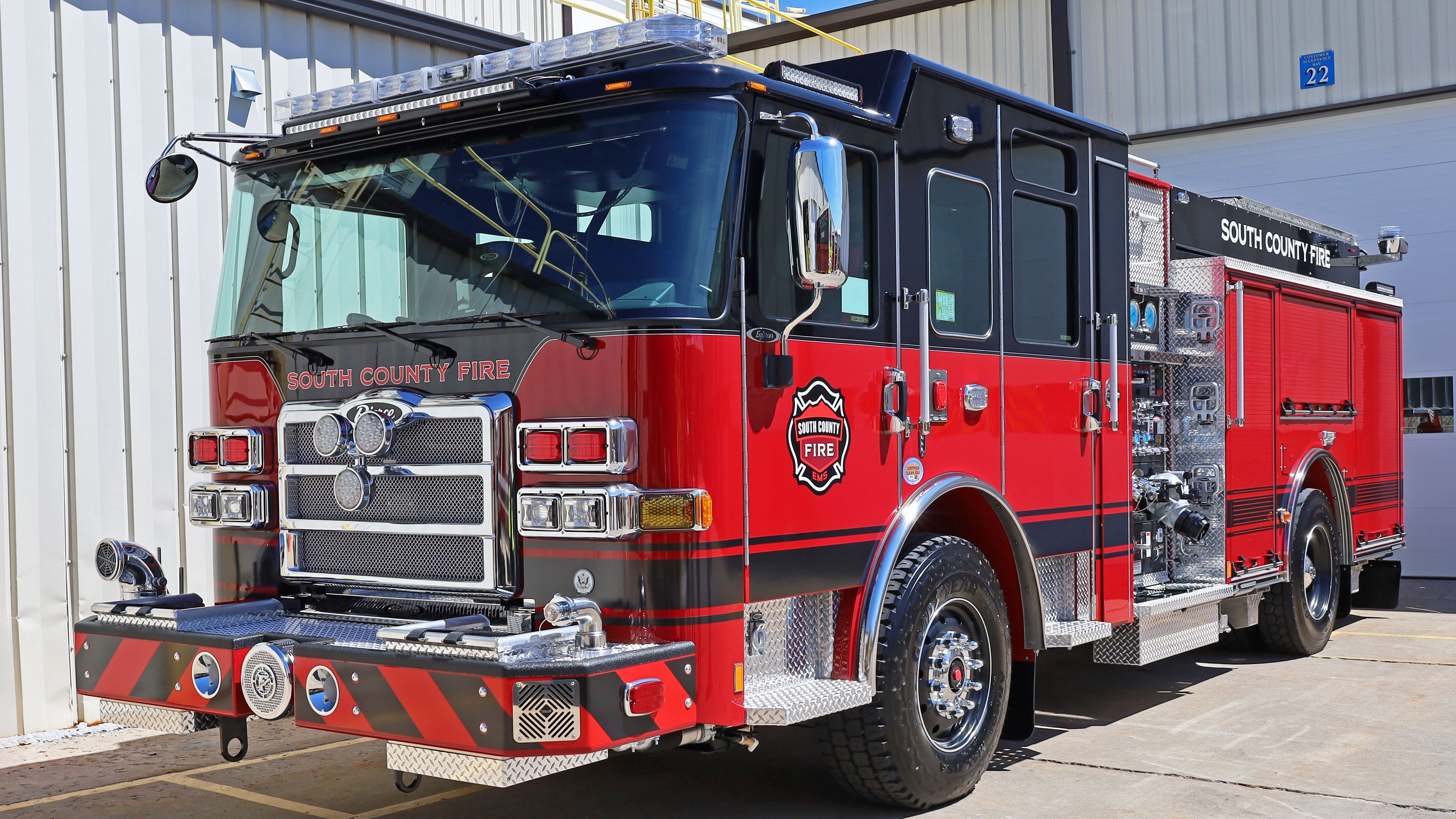 A red and black fire truck sitting in front of a garage door.