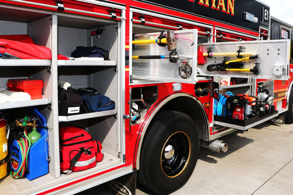 Passenger’s side of a Pierce PUC™ Fire Truck with storage compartments open showing tools and equipment. 