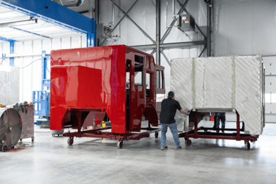A red painted cab of a fire truck in a factory setting.