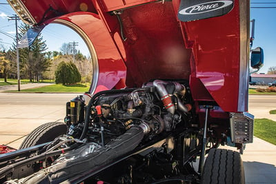 A red fire truck has the cab flipped open to show the fire truck engine. 