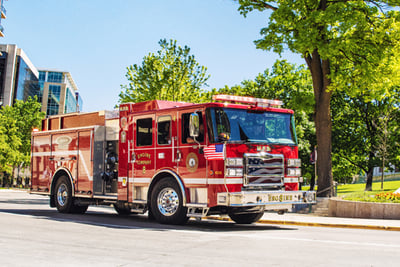 Red electric fire truck driving on a street in Madison, WI.