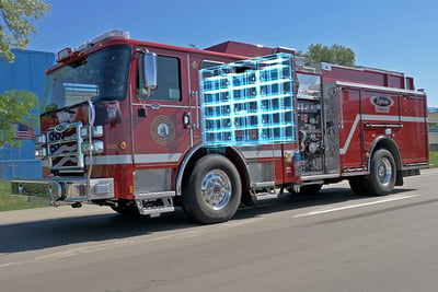 A red electric fire truck driving down the road has a blue image overlay that shows the battery at work.