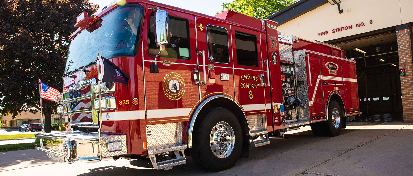 The Madison, Wisconsin red electric fire truck is parked outside fire station number 8. 