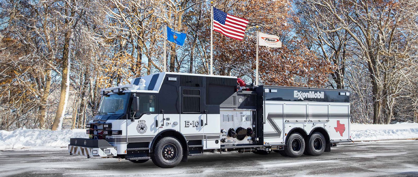 The black and white Exxon Mobil Baytown Refinery pumper fire truck is parked outside on an angle with snowy woods in the background.