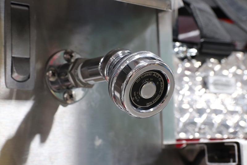 A fire truck shower head is centered in a photo on the exterior of a fire truck. 