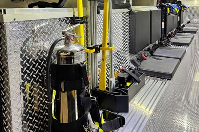 The interior of a heavy-duty-rescue walk-in apparatus shows mounted tools and seats for firefighters.