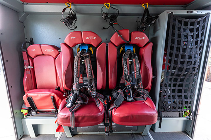 Interior of a crew cab on a fire truck with red seats and a compartment.