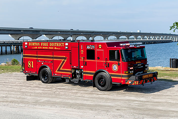 A Pierce Enforcer PUC Pumper parked next to water and a bridge.