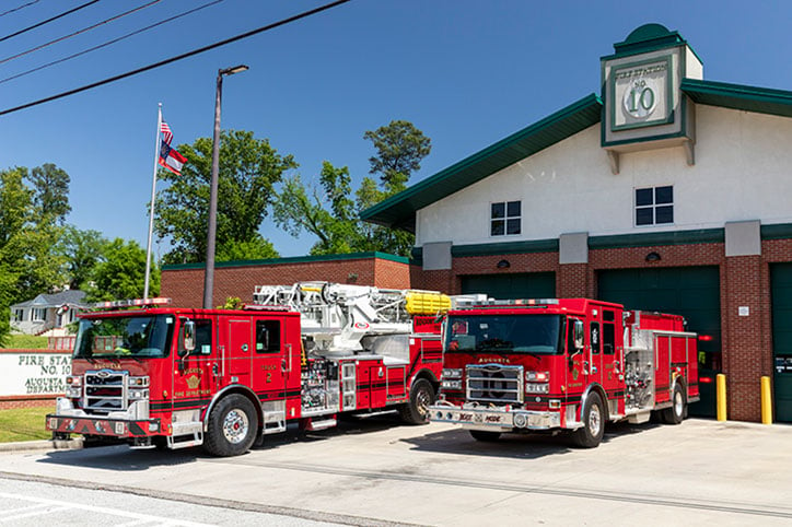 An Enforcer 100 Heavy Duty Aerial MidMount Tower and Enforcer Pumper parked in front of the Augusta Fire Department fire station.