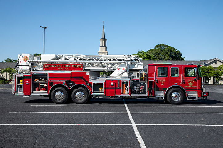 Enforcer 100 Heavy Duty Aerial MidMount Tower officers side of a fire truck with the compartments open showing equipment in a parking lot.