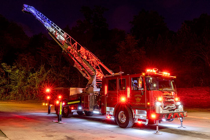Enforcer 100 Heavy Duty Aerial MidMount Tower with its red, white and blue rung lights on at night with the ladder extended up.