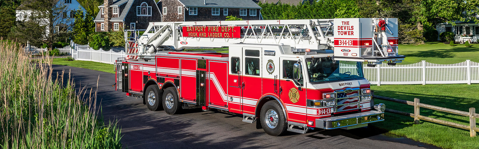 The front officer's side of a Velocity 100 Heavy-Duty Steel Aerial Platform parked on a  paved road in a neighborhood.