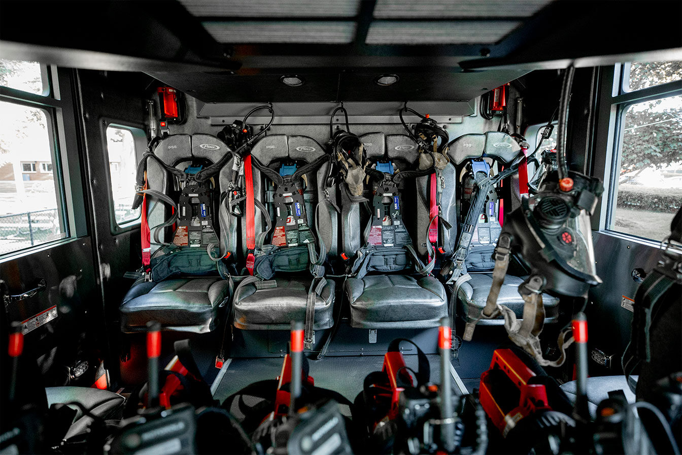 The inside of a fire truck crew cab with flashlights, radios and seats that hold SCBAs.