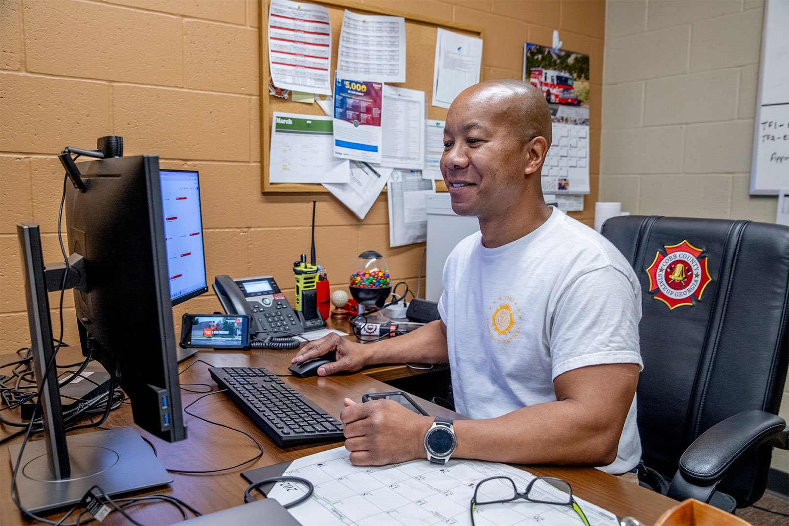 A firefighter working on a computer in an office at a fire station.