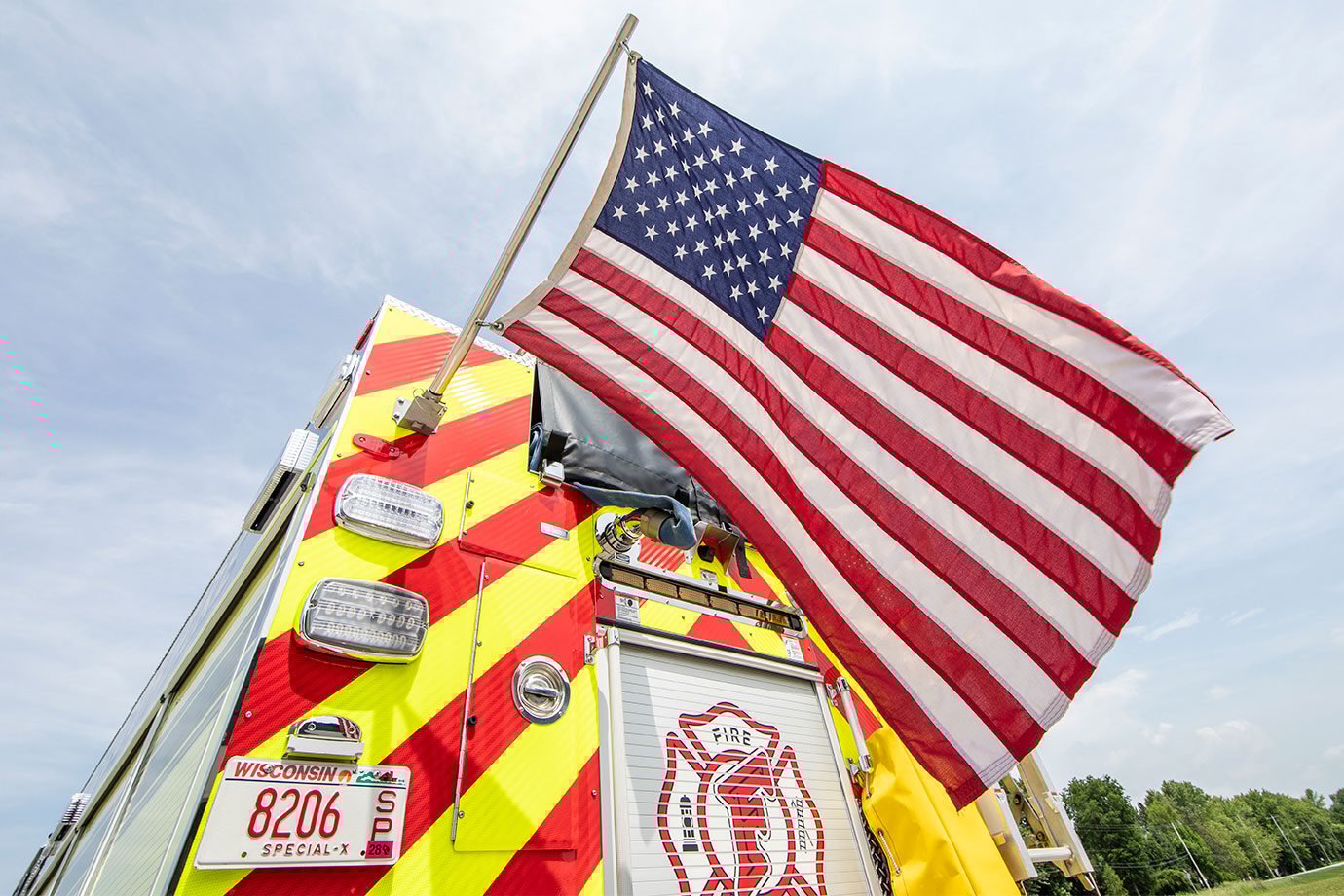 An American flag hanging off the rear of a fire truck.