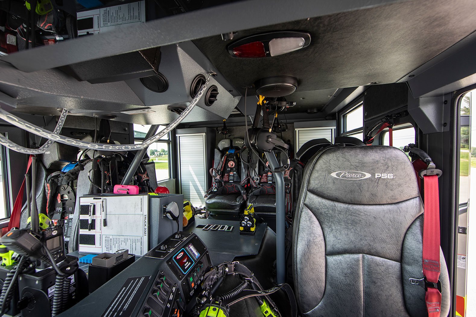 The crew cab of a fire truck with SCBAs in the officers and rear seat backs and headsets hanging from the ceiling.