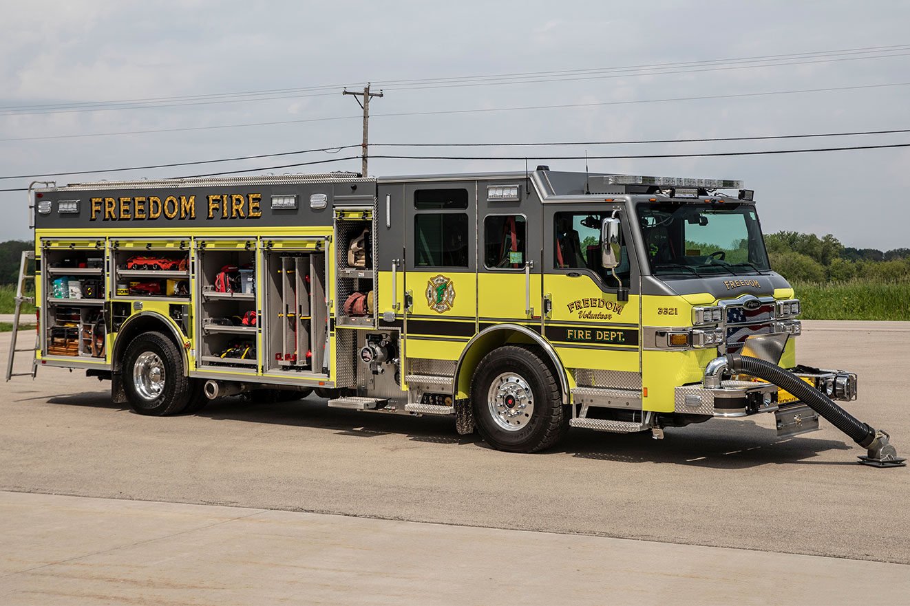 The officer's side of a fire truck with the hard suction extended out and the compartments open showing equipment and tools inside.
