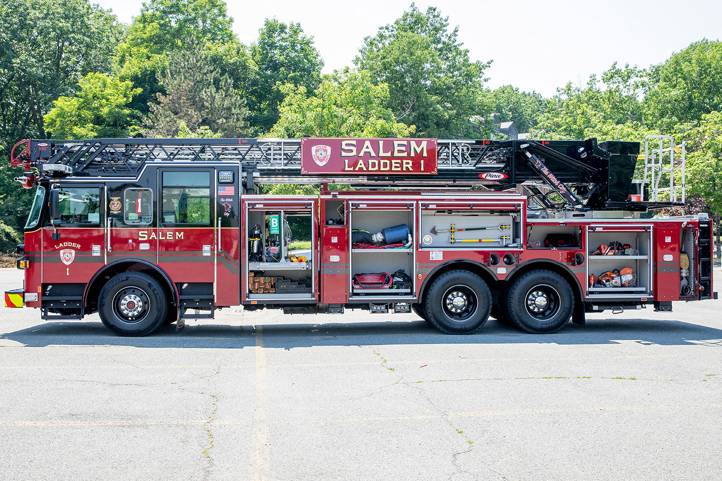 The drivers side of an Arrow XT 100 Heavy-Duty Low Profile Steel Aerial Ladder with the compartments open showing tools.