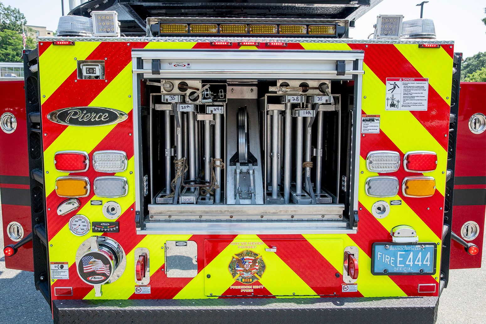 The rear of an aerial ladder fire truck with the compartment open showing ground ladders.