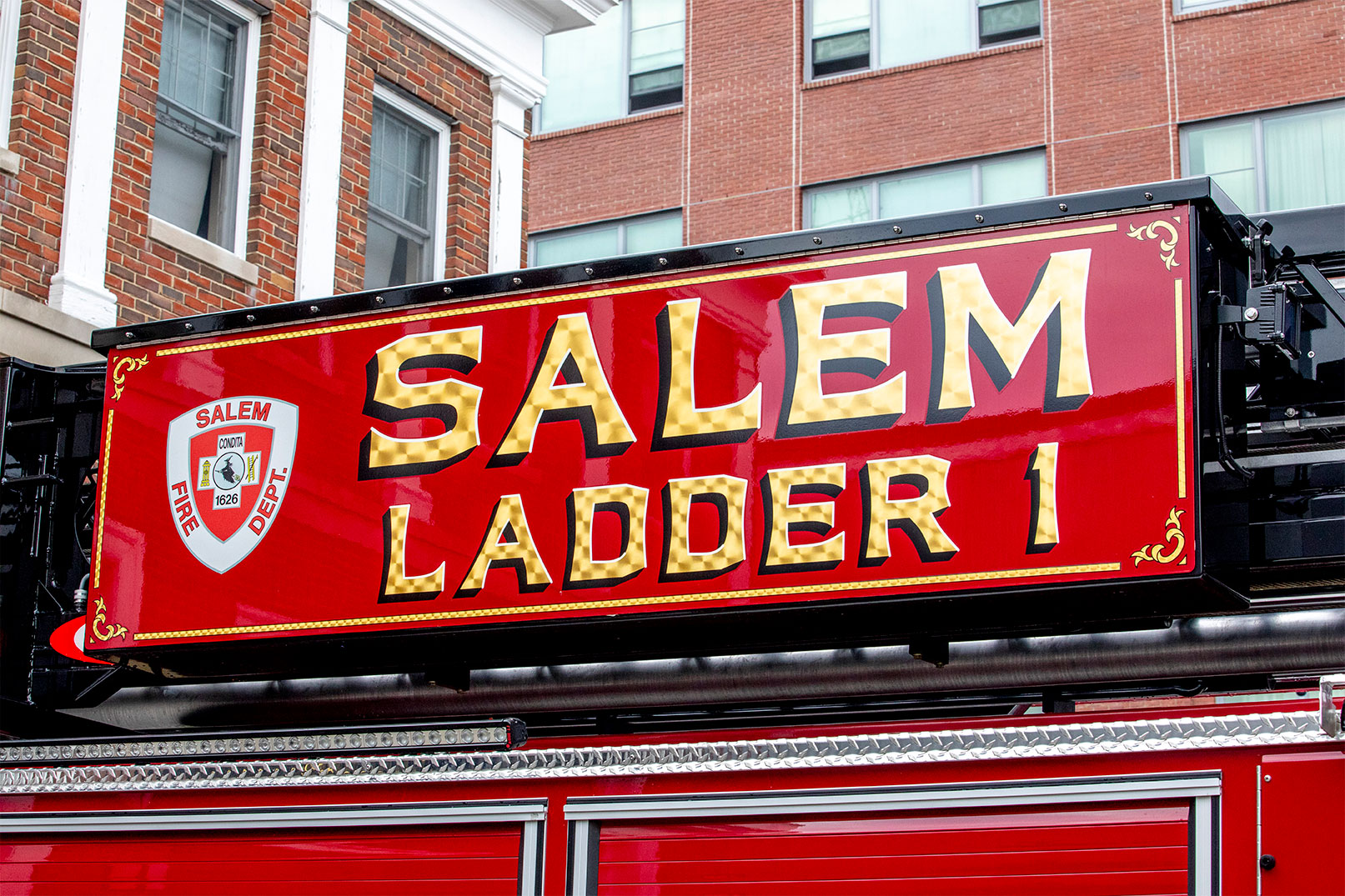 The side of an aerial ladder on a fire truck with a logo for Salem Fire Department on their Ladder One.
