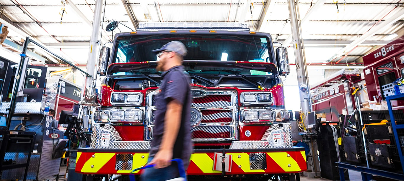 An employee walking in front of a fire truck in a manfacturing facility.