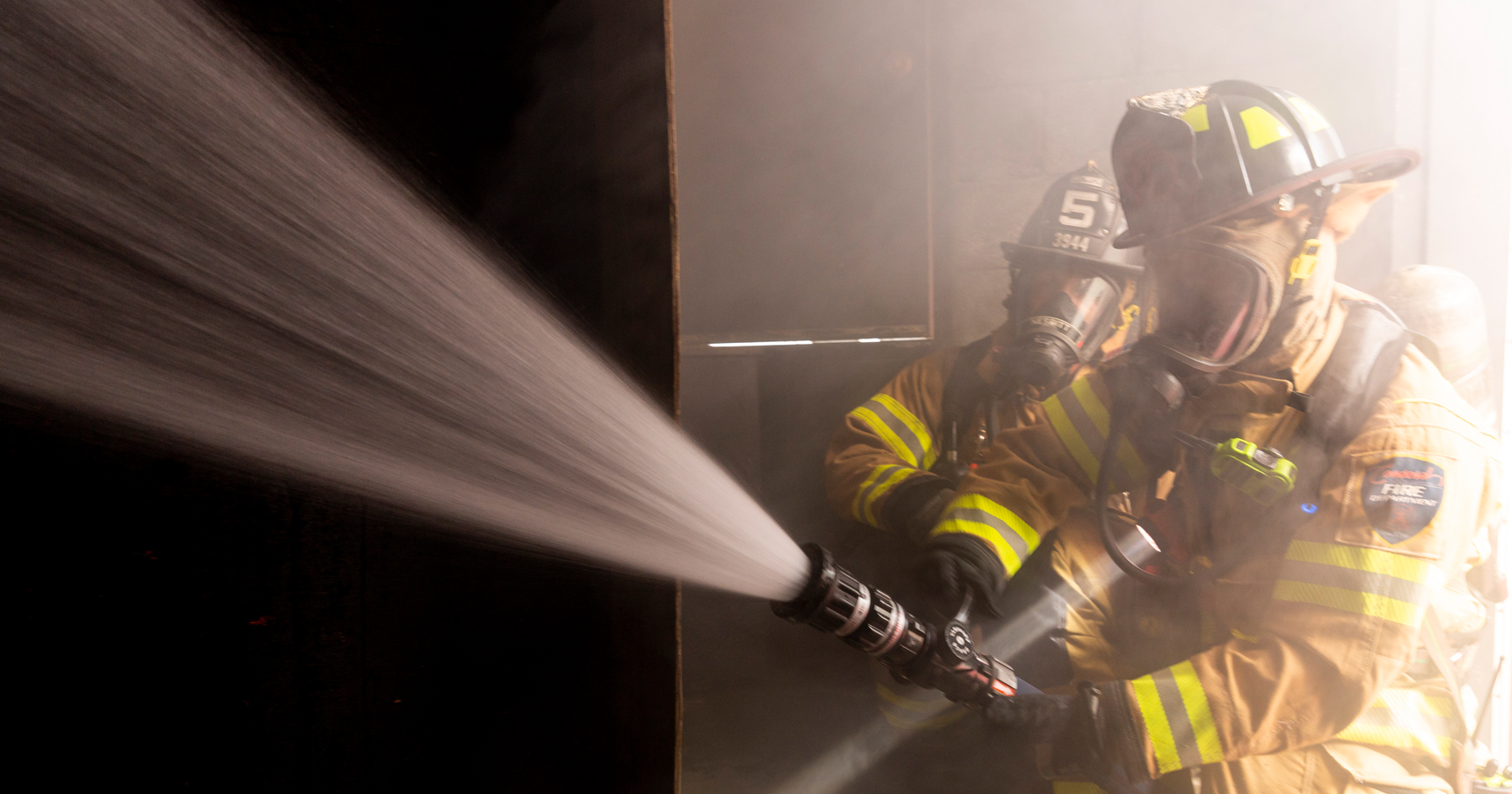 https://www.piercemfg.com/hubfs/Blog/Blog%20-%20Clean%20Cab/firefighters-in-turnout-gear-spraying-hose_featured.jpg