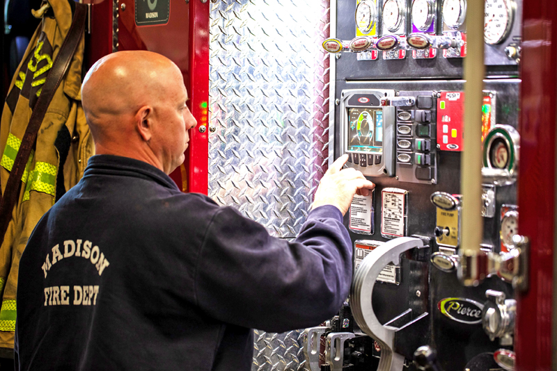 A firefighter operating the pump panel of an electric fire truck.