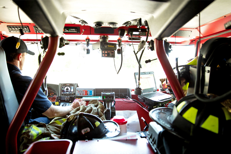 The inside of a electric fire truck with firefighters in the two front seats.
