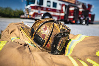 Firefighter gear with aerial ladder fire apparatus in background