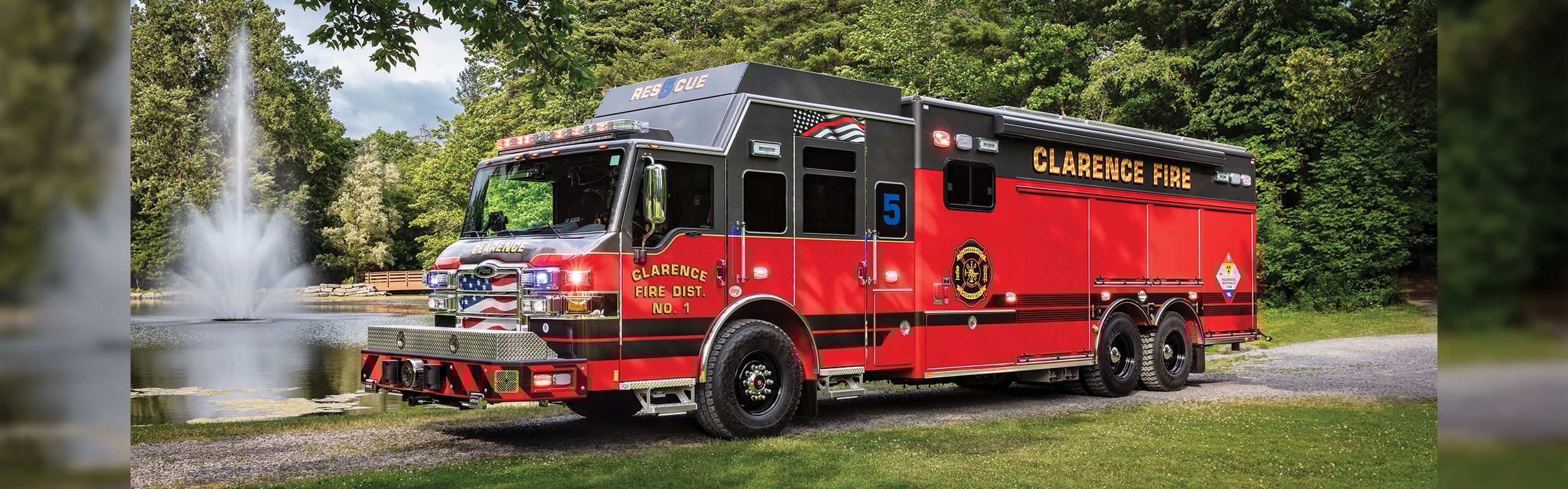The front driver's side of a Velocity Combination Walk-in Non-Walk-In fire truck parked next to a pond with a fountain on a