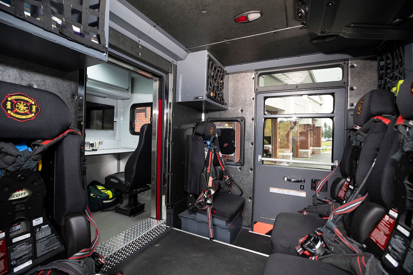 The crew cab of a Combination Rescue fire truck with five seats for firefighters with SCBA holders and a work area with computers.