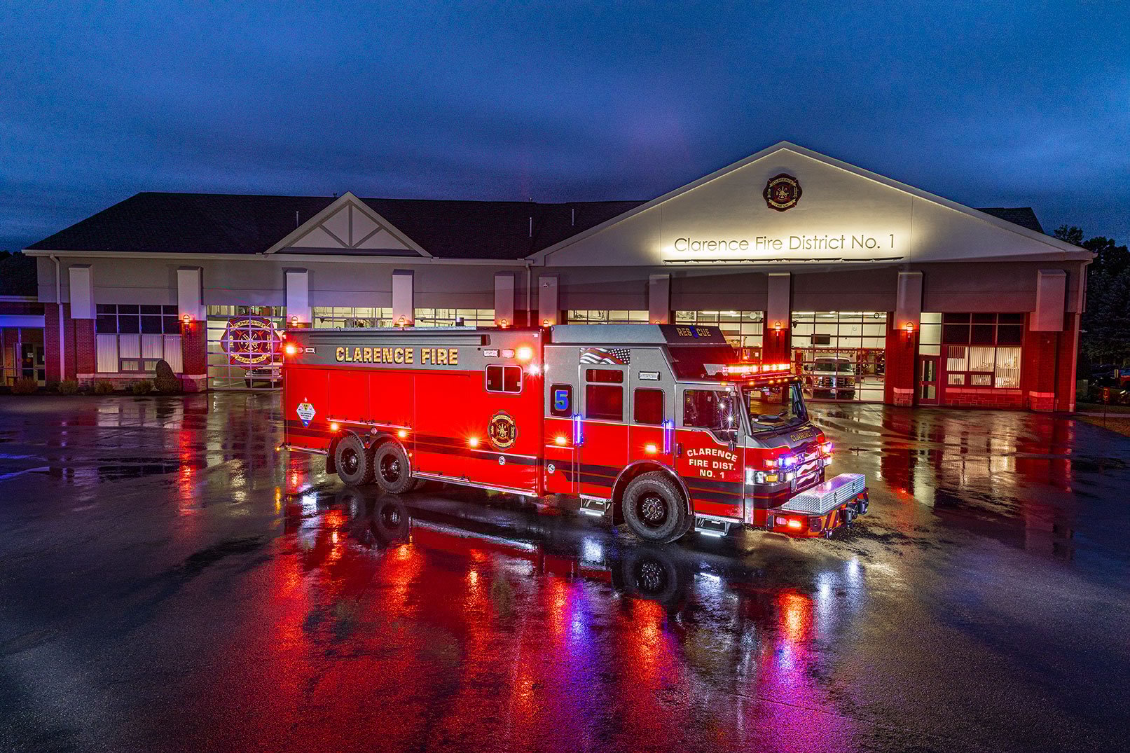The front officer's side of a Velocity Combination Walk-in Non Walk-in HDR with the lights on in front of a fire station at night.
