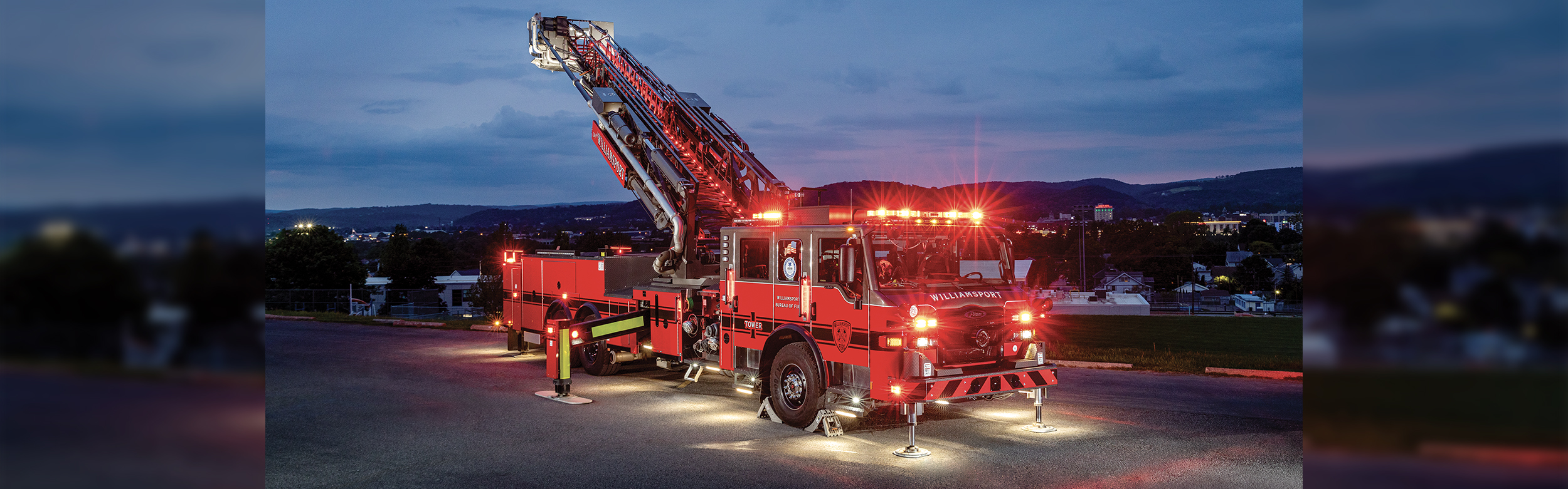 The front officer's side of a Velocity 100 Ascendant Aerial Tower with the aerial ladder extended and the lights on a
