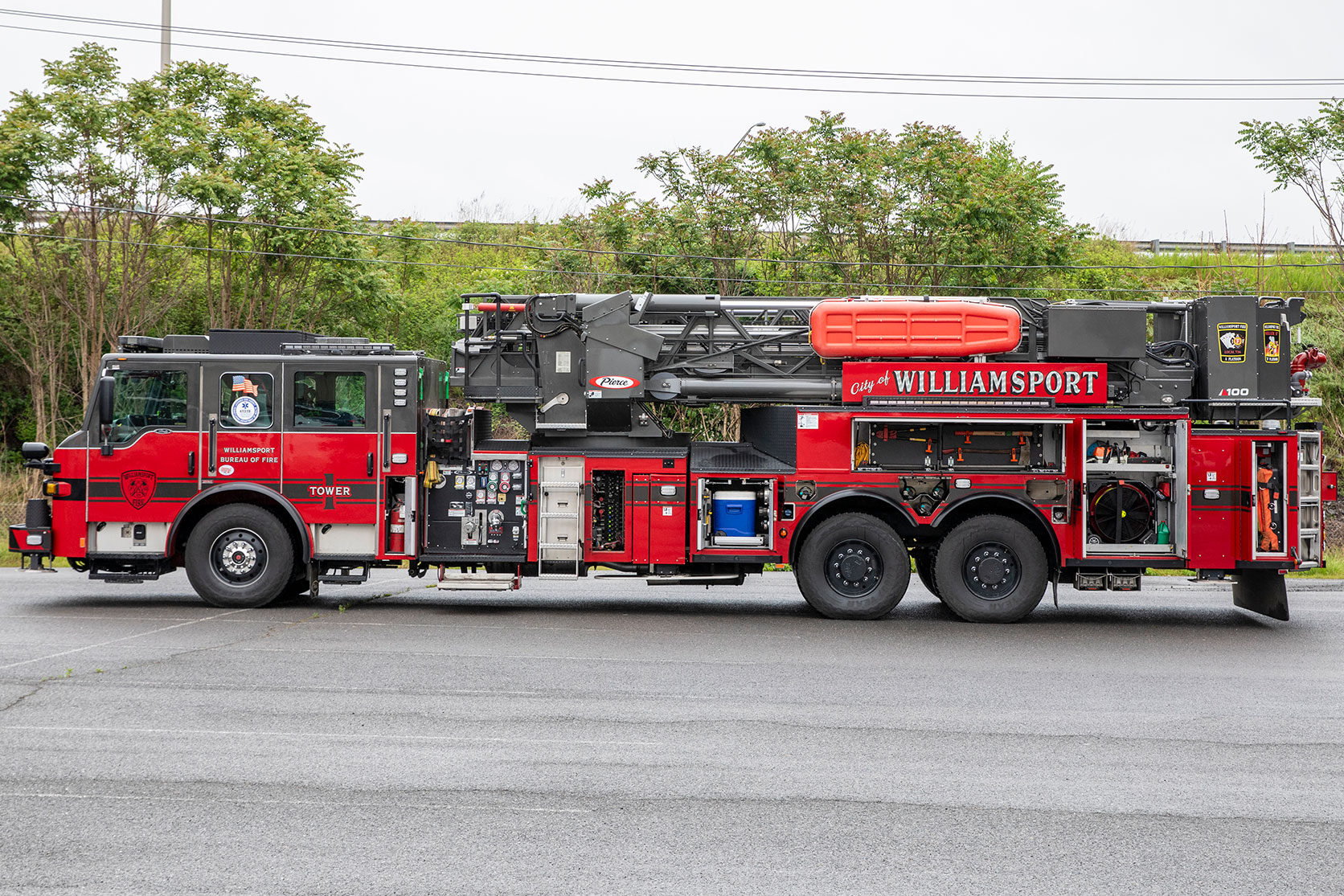 The driver's side of a Velocity 100' Ascendant Aerial Tower with the compartments open showing equipment inside.