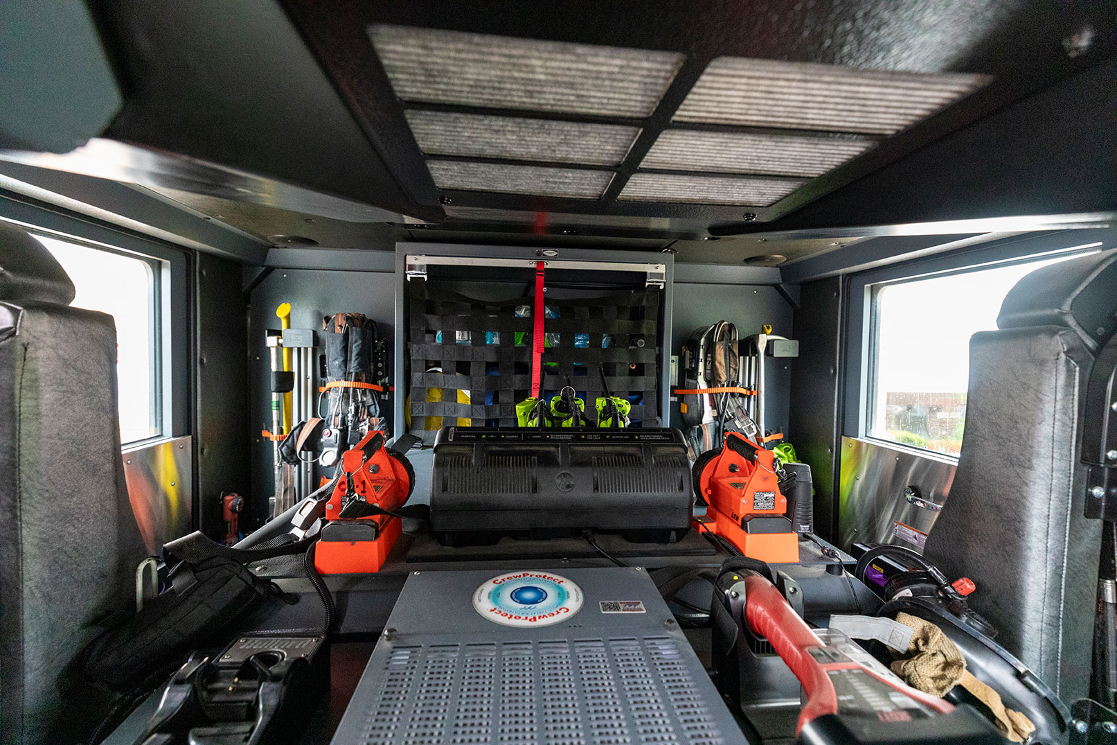 The inside of a fire truck with seats for firefighters and gear in the compartments.