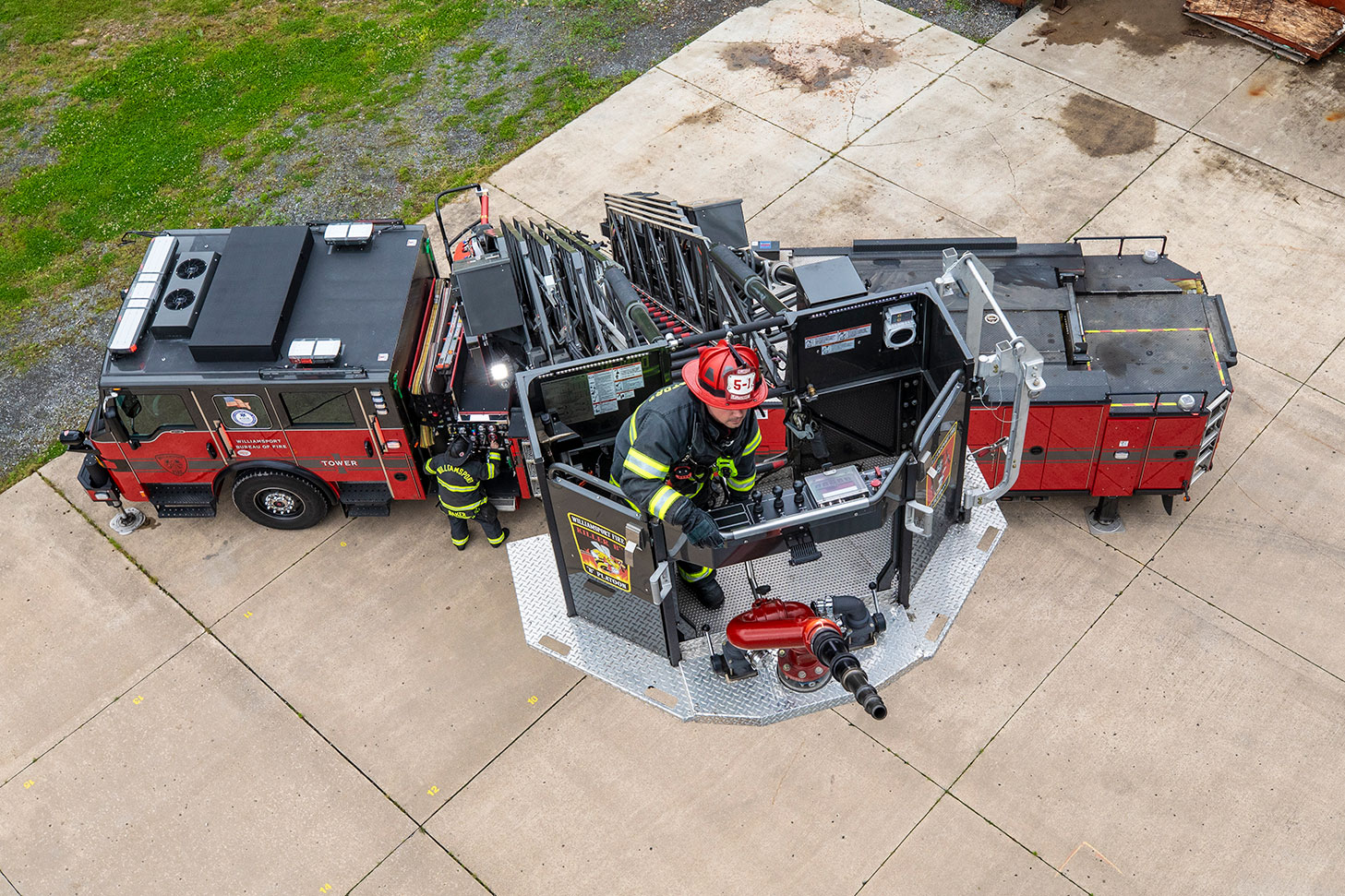The top of a 100' Ascendant Aerial Tower with the aerial extendend with a firefighter in turnout gear in the basket.