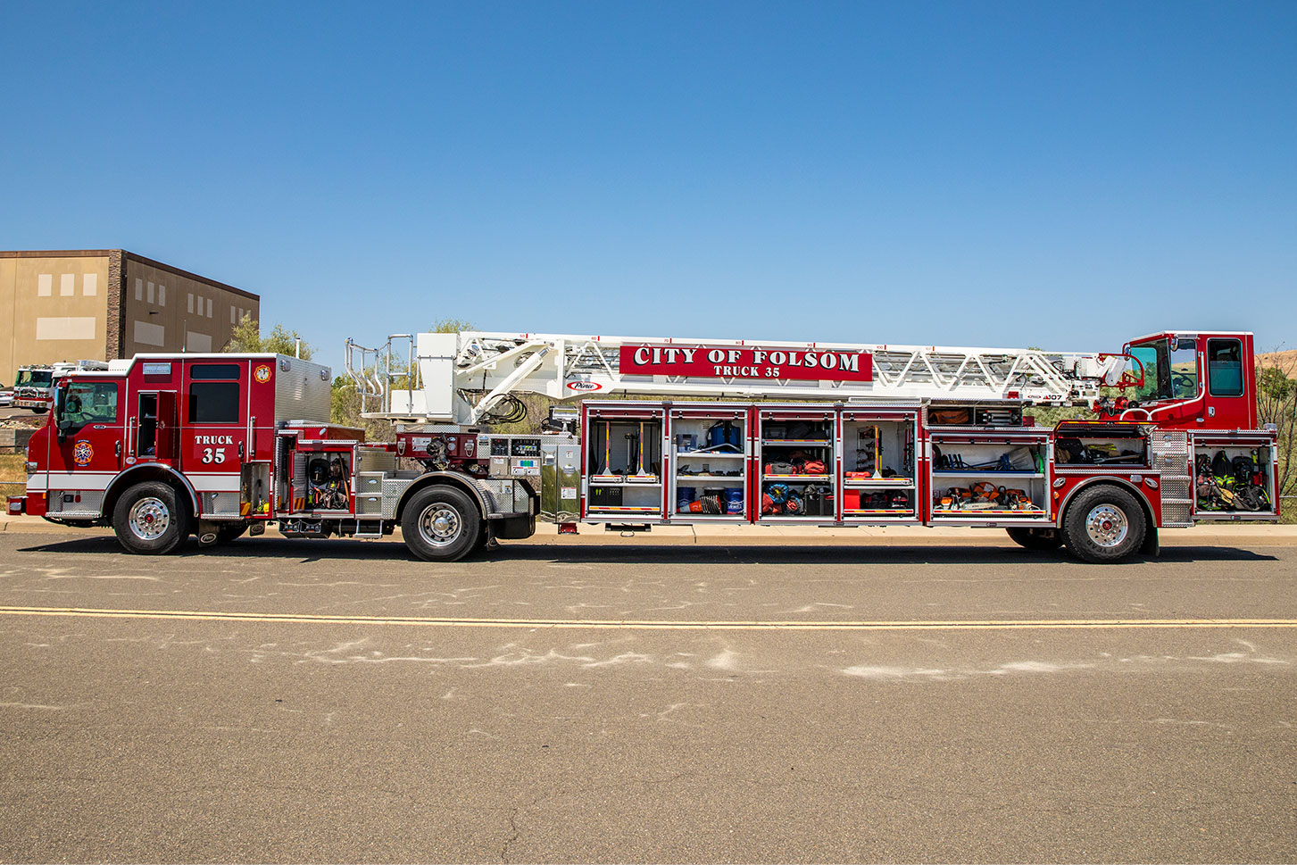 The driver's side of a Velocity Ascendant 107 Heavy-Duty Tractor Drawn Aerial with the compartments open showing equipment.