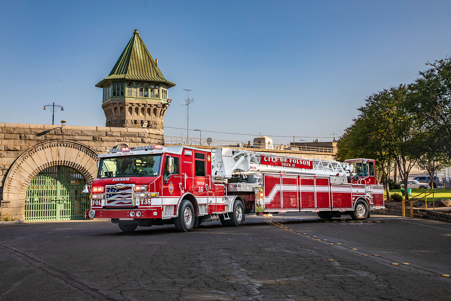 The driver's side of a Velocity Ascendant 107 Tractor Drawn Aerial parked in front of a historic brick building on a sunny day.