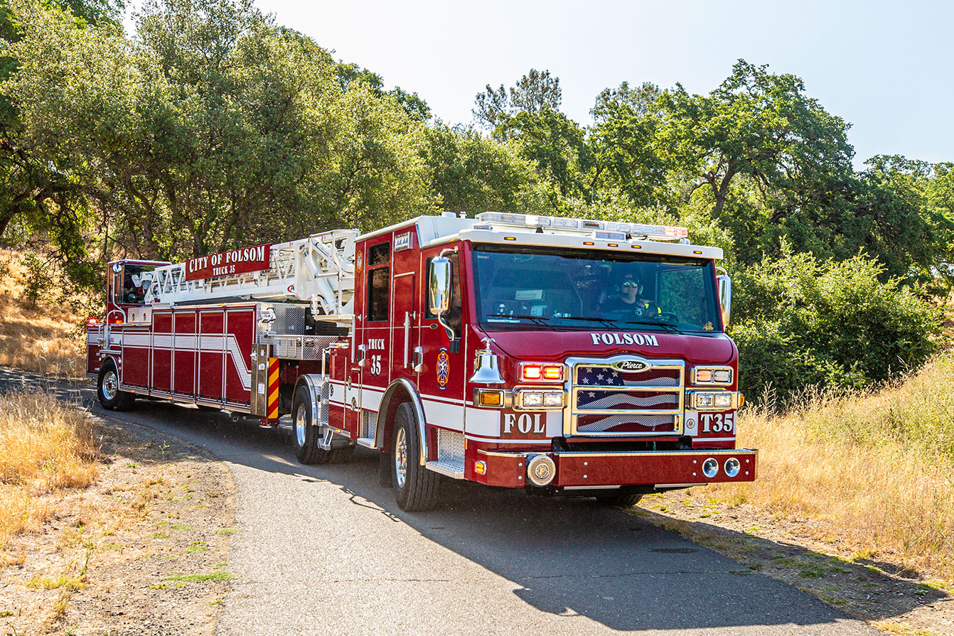 The front officer's side of a Velocity Ascendant 107 Heavy-Duty Tractor Drawn Aerial driving down a narrow rural road.