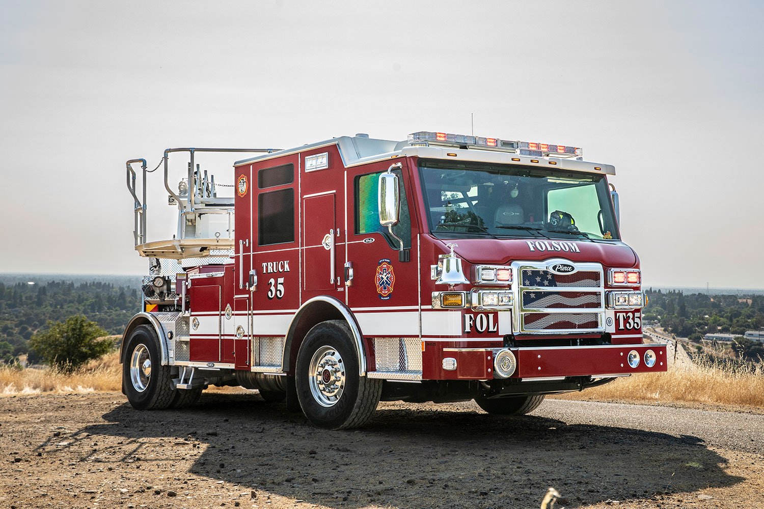 The front officer's side of a Velocity Tractor Drawn Aerial turning left at the top of a hill in a rural area.