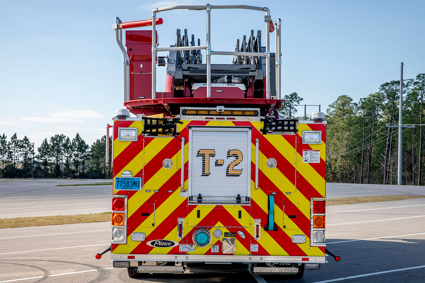 The rear of an aerial fire truck with a chevron pattern in a parking lot on a sunny day.