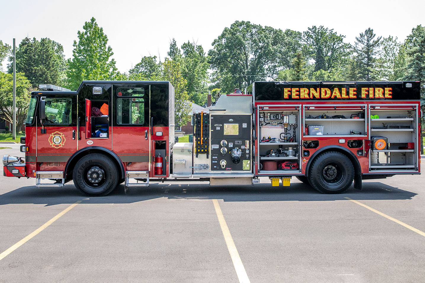 The drivers side of a Saber Top-Mount Pumper with the compartments open showing equipment and tools inside.