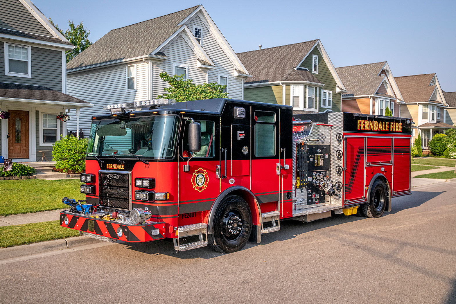 The front drivers side of a Saber Pumper fire truck driving down a residential neighborhood street.